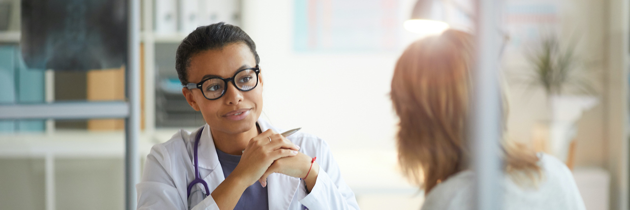 Doctors Should Have Better Explained My Schizophrenia Diagnosis Black doctor sitting at a table and