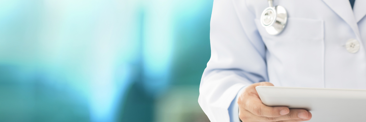 White male doctor holding tablet.