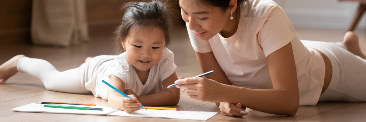 Young Asian mother and daughter drawing with pencils.