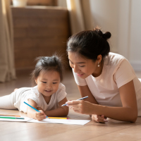 Young Asian mother and daughter drawing with pencils.