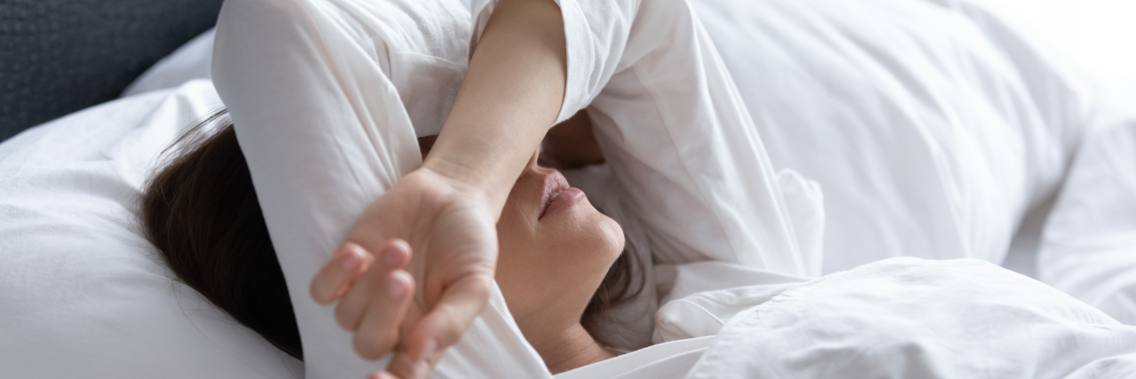 We Should Normalize Talking About Miscarriage and Child Loss a sleepless woman with her arms over her face