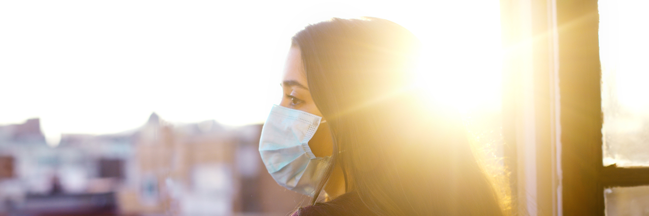 Pandemic Changes That Have Helped the Disability Community Woman wearing mask looking out at city.