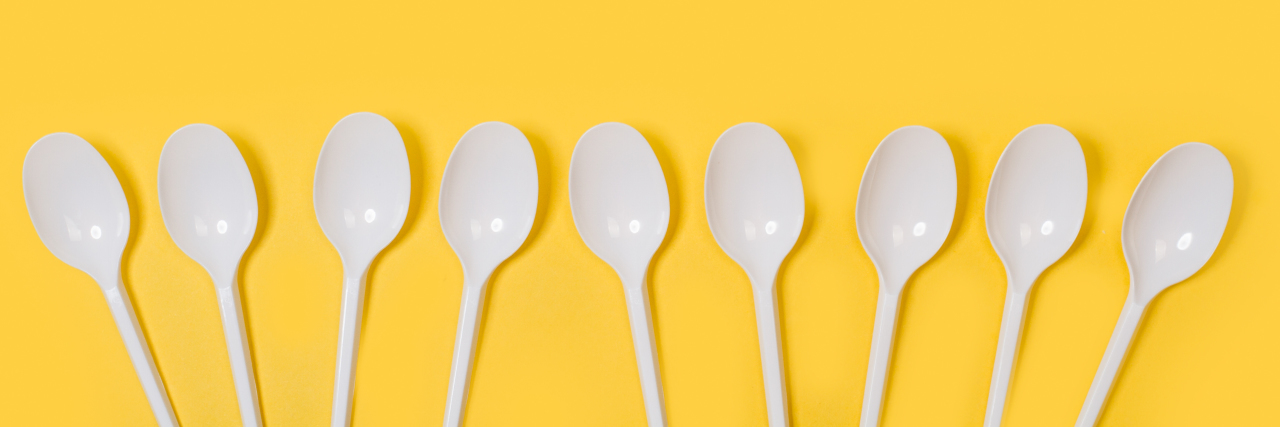 Surviving Abuse and Gaslighting as an Autistic Person Disposable white plastic spoons on a yellow background.
