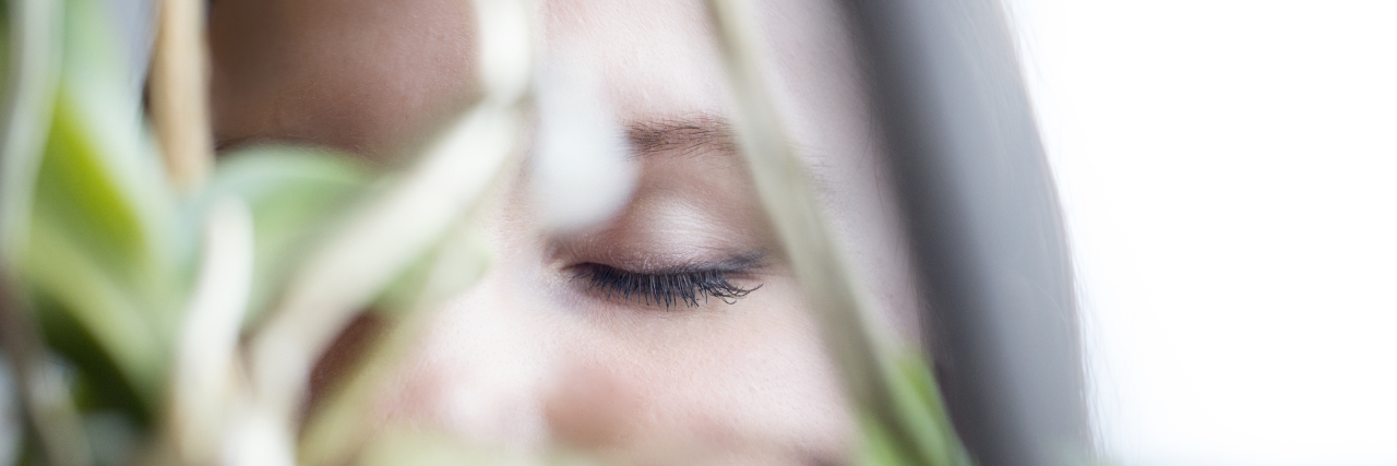 What It's Like to Be Trapped in Your Own Head With Rumination a woman with her eyes closed focused through plants