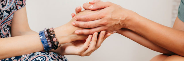 a close-up of women holding hands in support