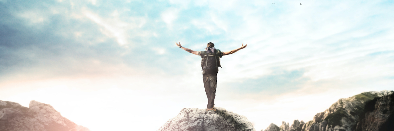 Man on top of a mountain with arms open wide