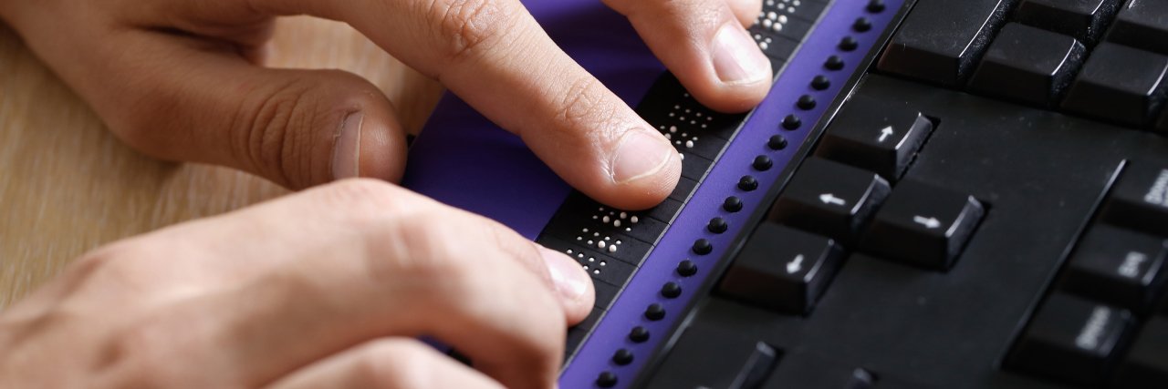 KHN: Covid Vaccine Websites Violate Disability Laws Blind person using computer with braille computer display and a computer keyboard.