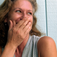 photo of a woman laughing set against pastel blue green wooden background