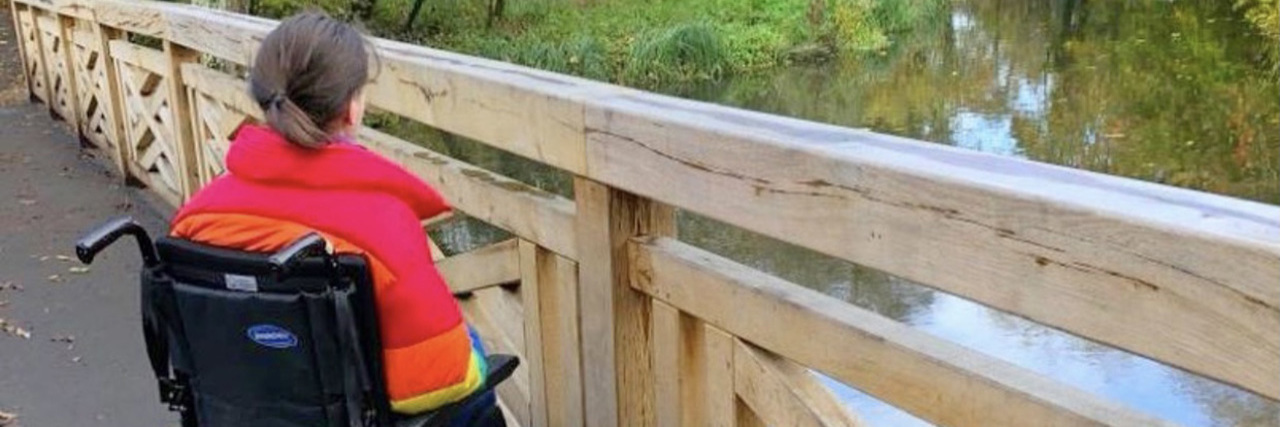 Questions for Those Who Discriminate Against People With Disabilities Rebecca sitting in her wheelchair on a bridge looking out at the water.