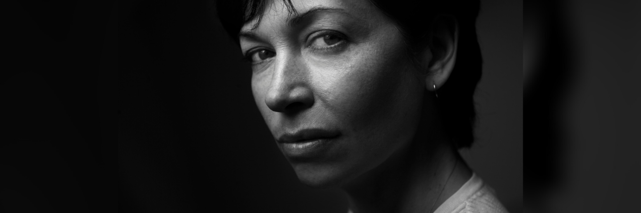Don’t Say Child Abuse Is OK Because It ‘Happened in the Old Country’ black and white photo of a short haired mature woman looking serious against dark background