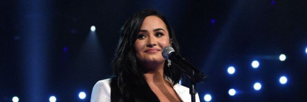 Demi Lovato in a white dress onstage