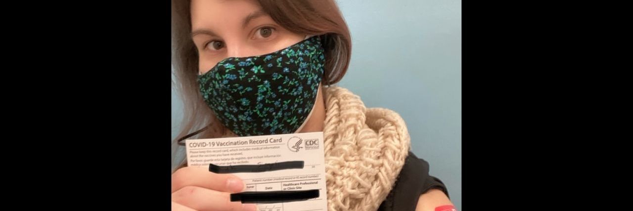 Getting the COVID-19 Vaccine With Medical PTSD a young woman holding up her COVID-19 vaccine card