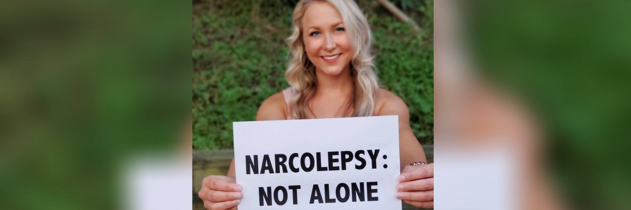 Brooke holds up a sign that says "Narcolepsy, Not Alone."