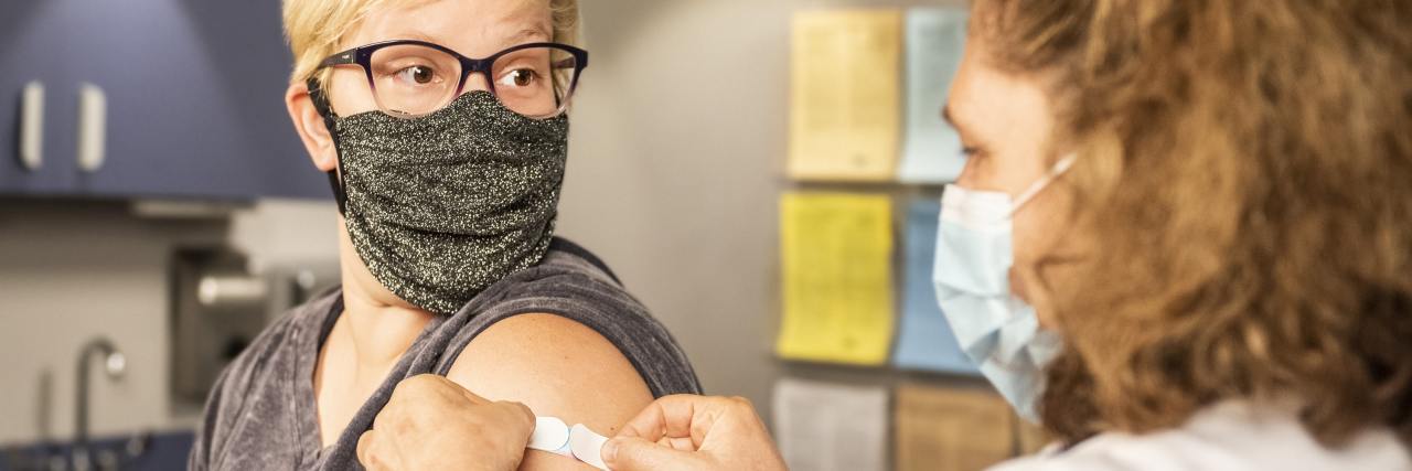 It’s OK If the COVID-19 Vaccine Triggers Your Fear of Needles photo of a nurse and a woman after recieving a vaccine, receiving a plaster