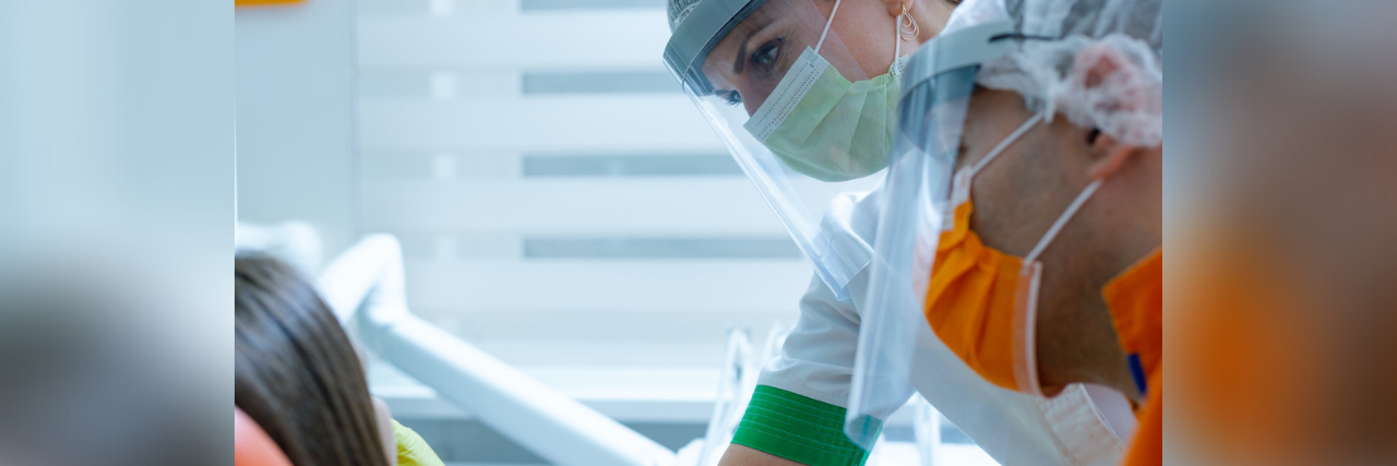 The Importance of the Provider-Patient Relationship A woman wearing a mask and face shield gives a dental exam to another woman, who we can only see the back of her head