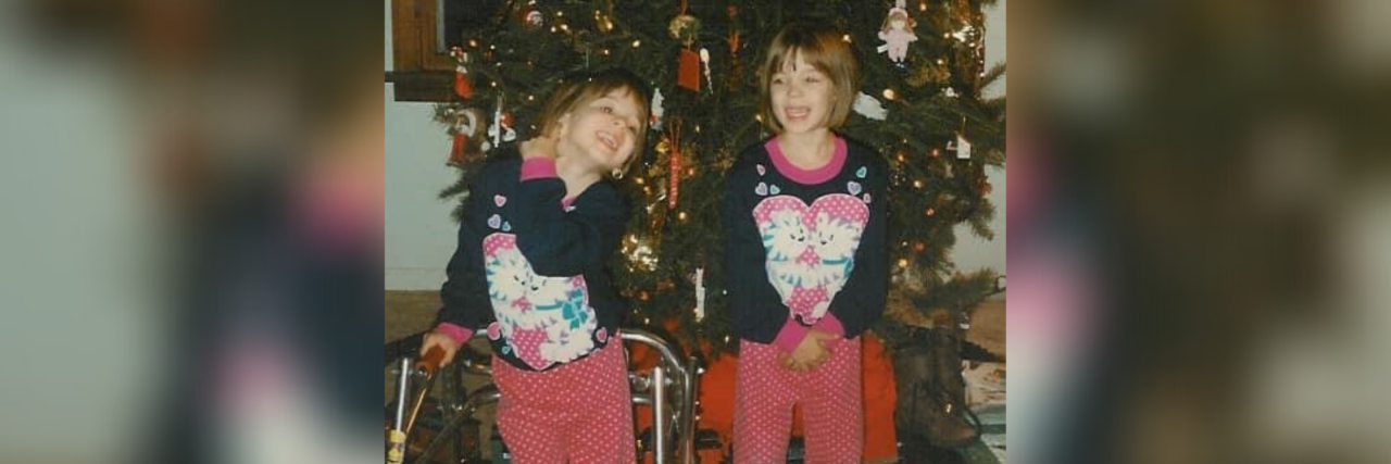 Karina as a child with her sister in front of the Christmas tree.