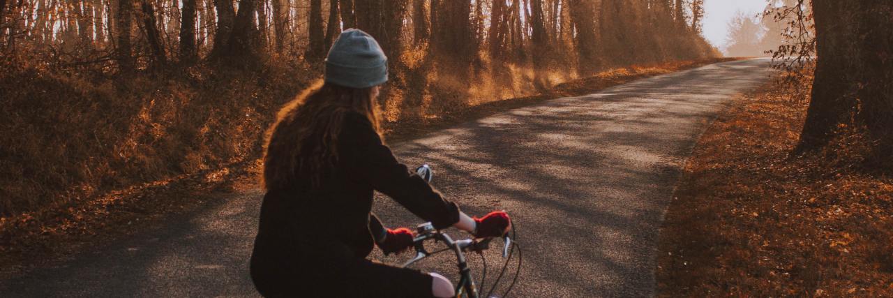 It's OK To Have Setbacks in Anxiety Recovery photo of a woman on a long road at sunset with bare trees, sitting on a bicycle