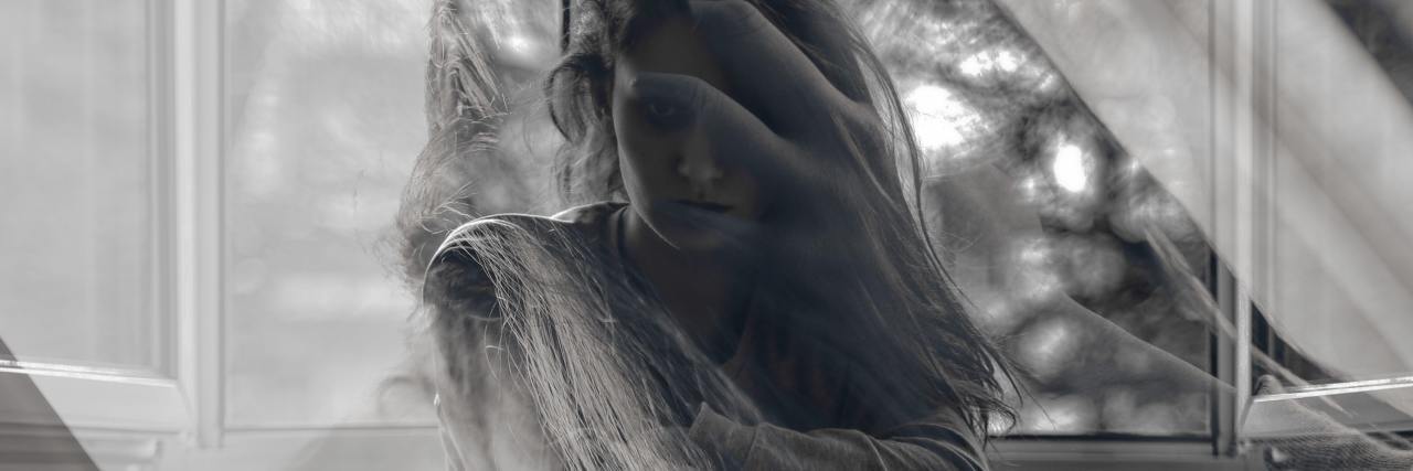 black and white double exposure photo of a woman sitting on a chair looking sad