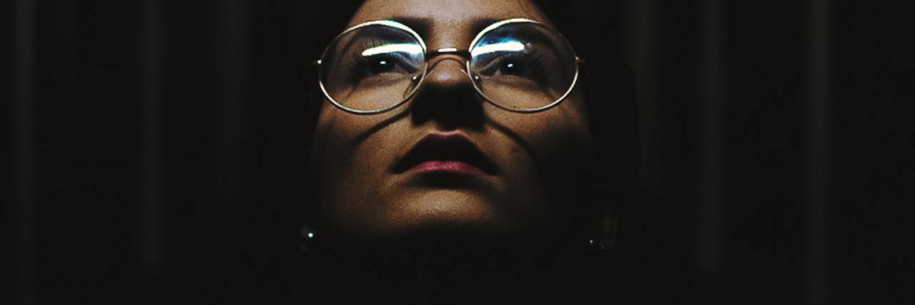 Toxic Hyperfixation With Borderline Personality Disorder photo of a woman in a dark corridor, face illuminated and looking up into light