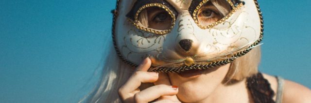 photo of a woman covering her face with a rabbit masquerade mask