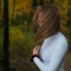 photo of a woman standing in woods with hair covering her face