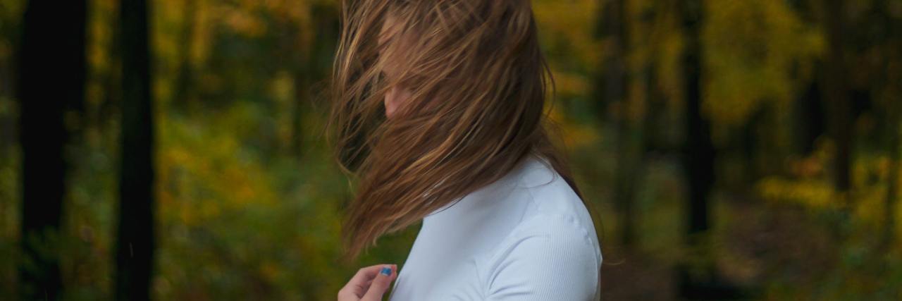 photo of a woman standing in woods with hair covering her face