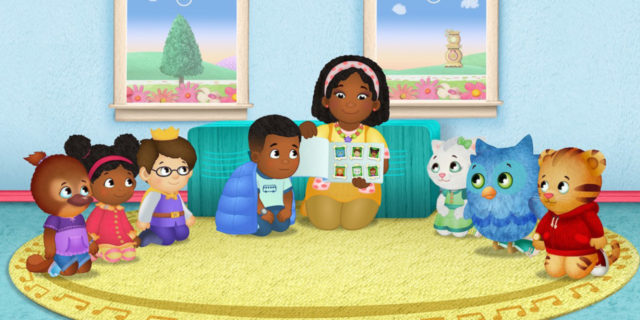 A scene from Daniel Tiger's Neighborhood with Max and all of the o there characters on a rug listening to a story.