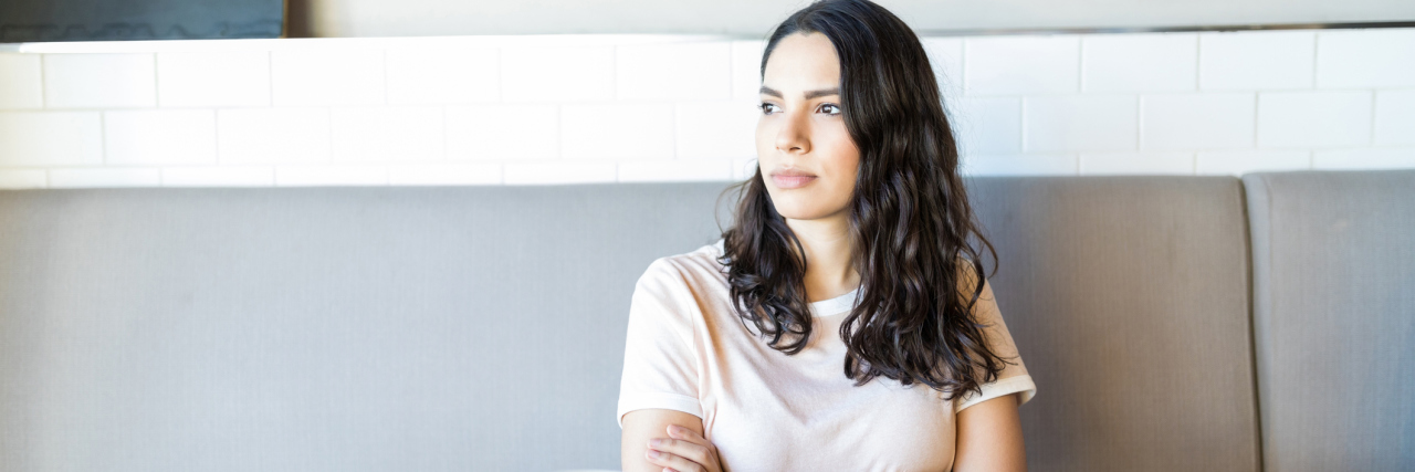 Meeting New People and Dating With Borderline Personality Disorder A young white woman sitting at a cafe with arms crossed, waiting for a date