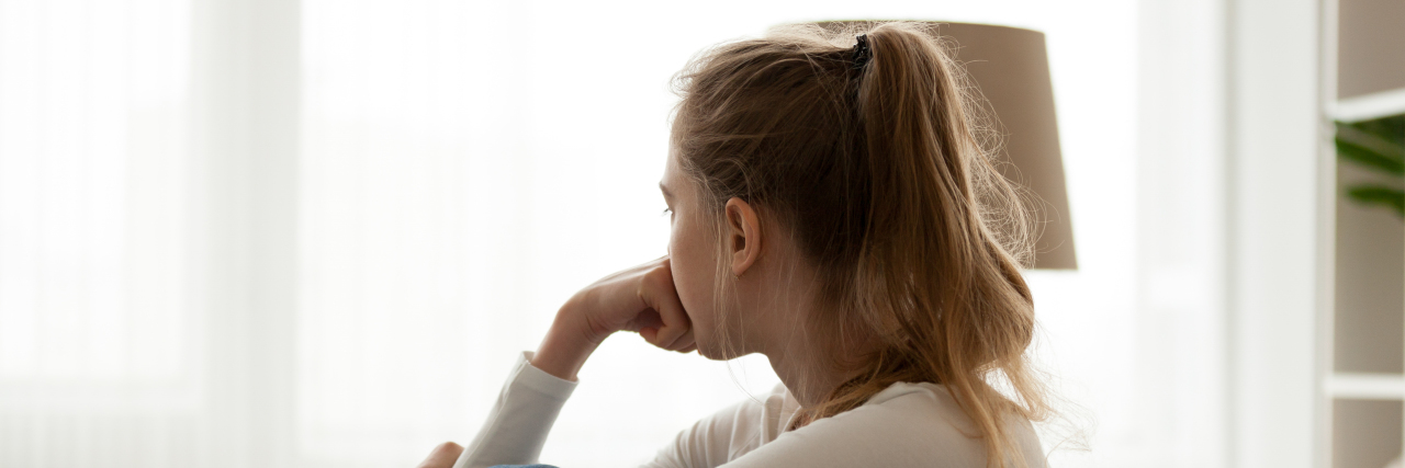 Working Through Feelings of Shame in My Life With a Disability Sad woman sitting on couch alone at home.