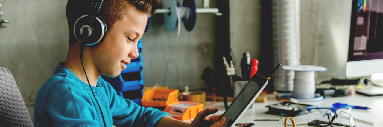 How Strengths-Based Education Can Help Students on the Autism Spectrum Boy with headphones holding digital tablet.
