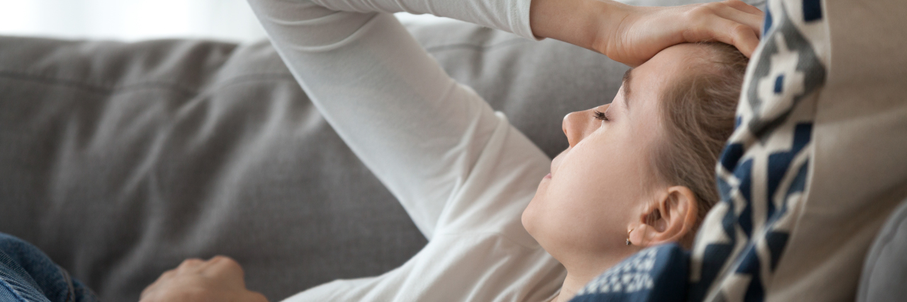 Our Chance to Change Infectious Disease Narratives Amid COVID-19 a woman lying on her couch not feeling well
