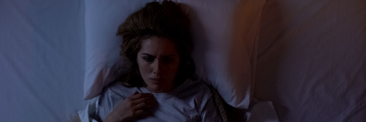 A young white woman lying in bed at night still awake