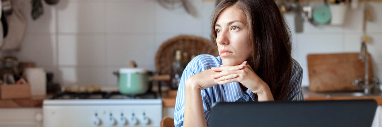 How I Create Structure in My Bipolar Days Woman sitting at kitchen table in front of a laptop, looking to the side