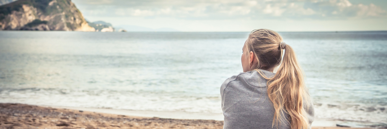 Letting Go of Control With Infertility Pensive woman sitting on beach looking into the distance