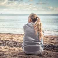 Pensive woman sitting on beach looking into the distance
