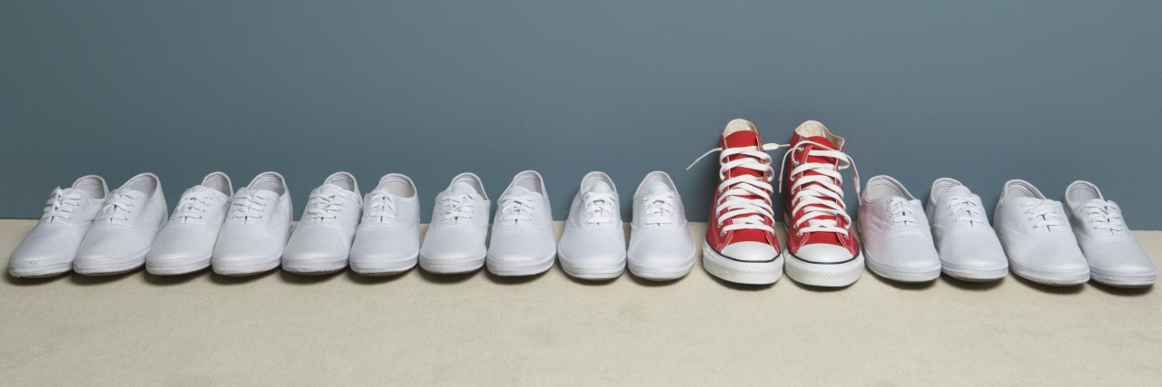 Red Converse shoes in a row of white Keds.