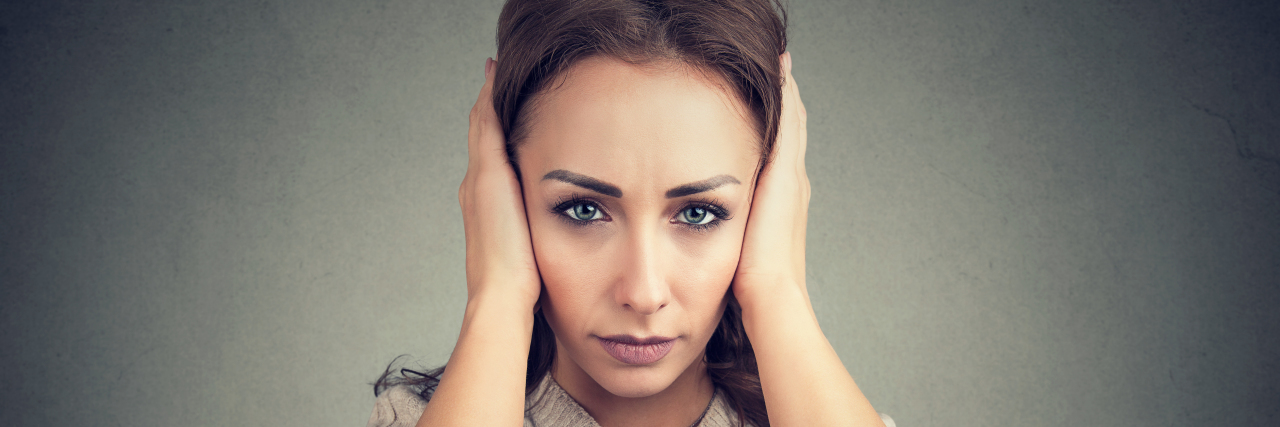 Ways Complex PTSD Can Present Itself a woman holding her ears