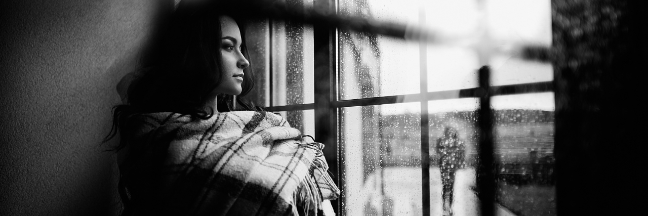 black and white photo of woman looking through window