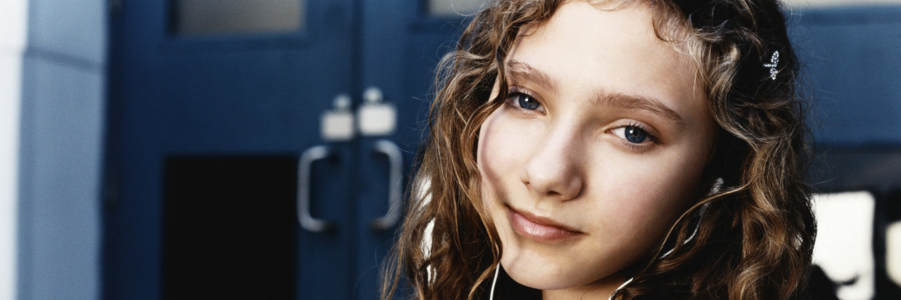 Teen girl outside high school doors.