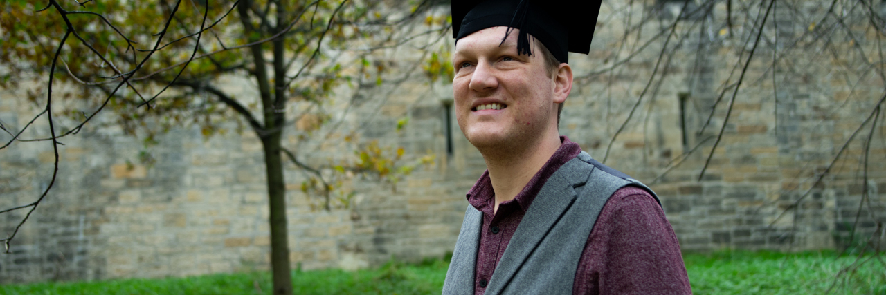 photo of the contributor holding a scroll and wearing a motorboard hat from a graduation