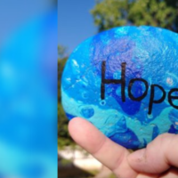A blue painted rock with the word "hope" written on it