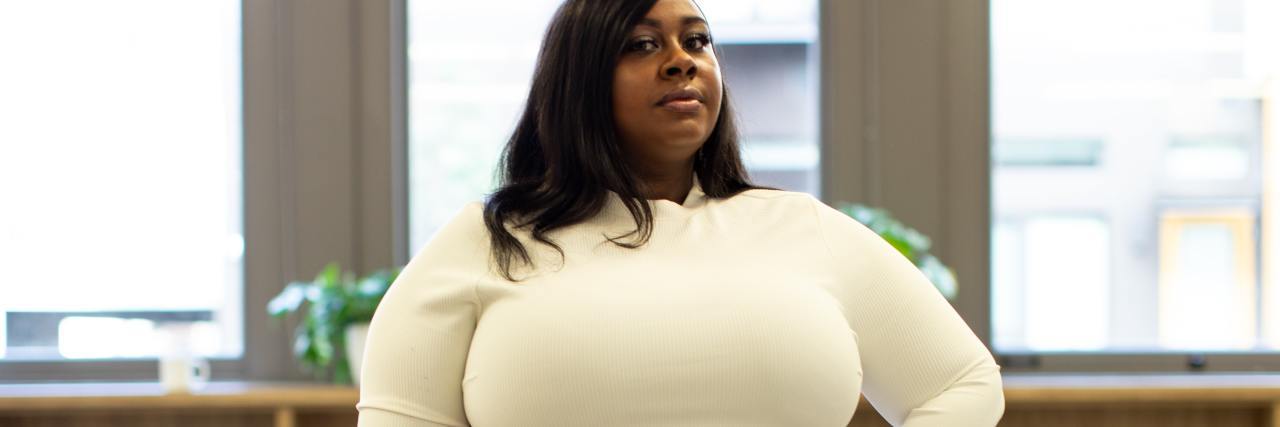 photo of a plus size Black woman looking into the camera with her hand on her hip