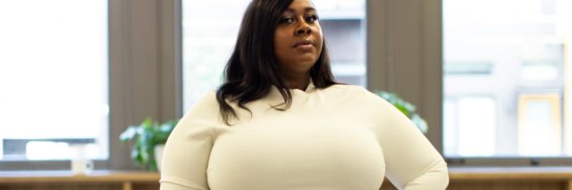 photo of a plus size Black woman looking into the camera with her hand on her hip