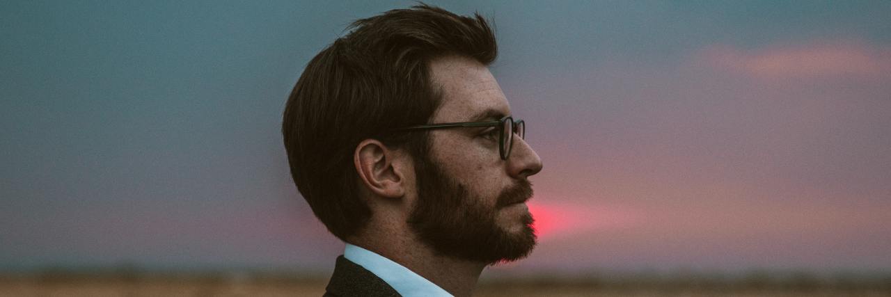 How to Challenge the Lies of Depression and Suicidal Thoughts Side profile of a young white man in a suit and glasses at sunset