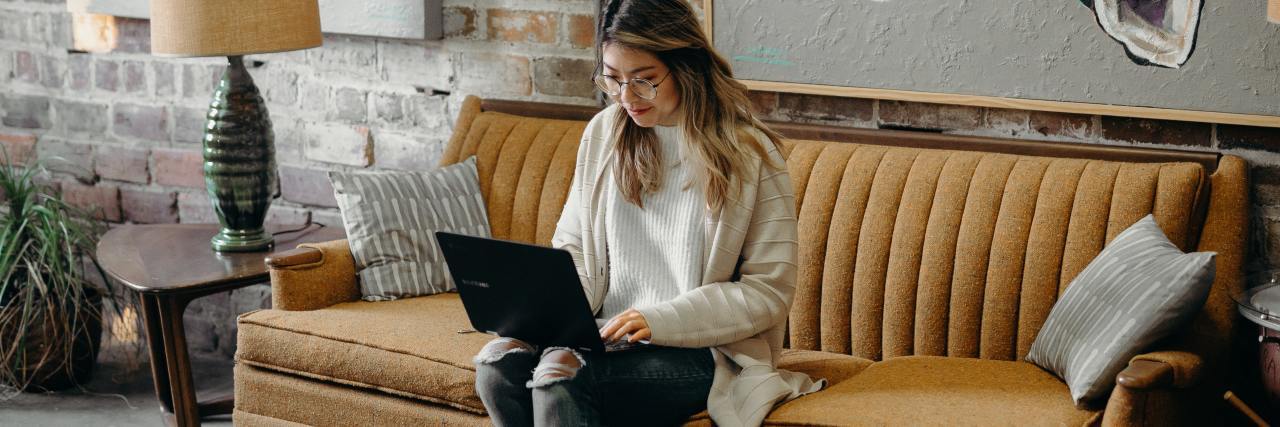 photo of a woman sitting on a sofa with a laptop