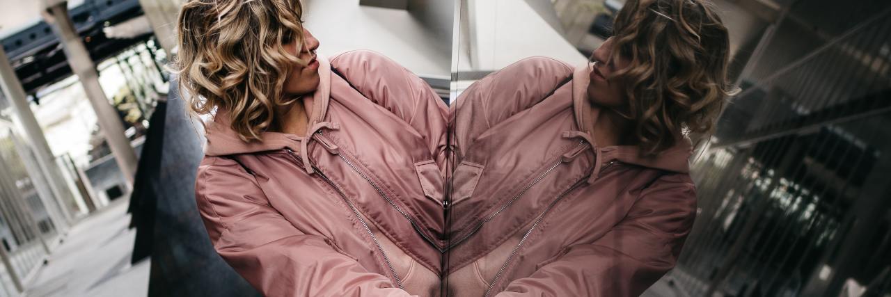 The Positives of Having an 'Official' Mental Health Diagnosis photo of woman looking at her reflection in the corner of a building