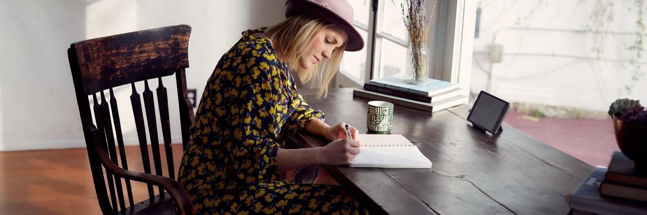 photo of a woman writing at a wooden table