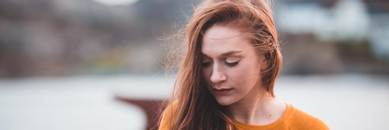 My Chronic Fatigue Is Not a 'Gift' A young, white woman with long red hair standing outside looking down