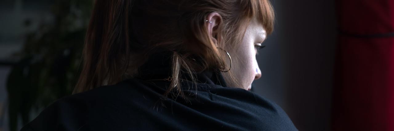 photo of a woman looking over her shoulder in fear, facing way from the camera