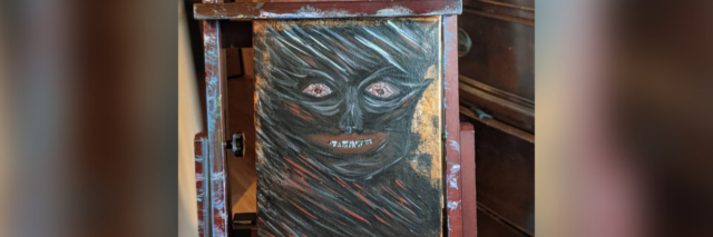 Photo of contributor's painting of demon face with red eyes on easel